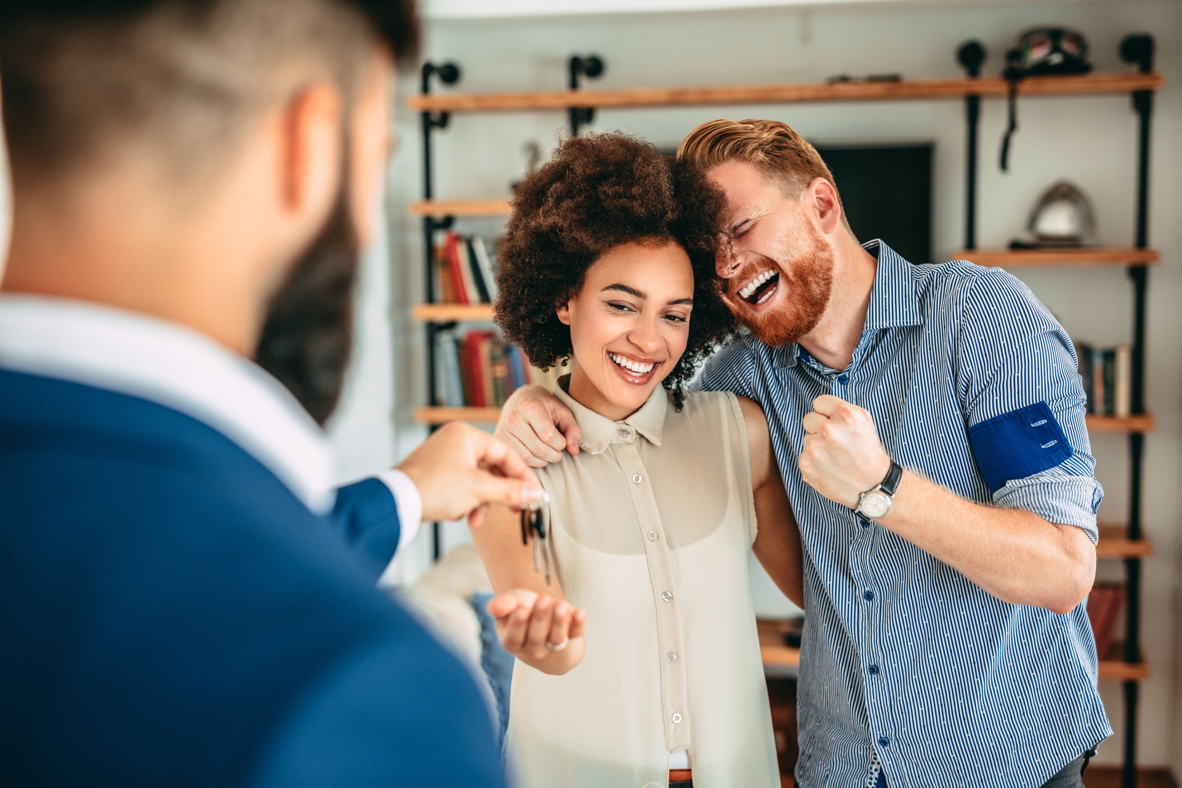 Man and Woman laughing and smiling as being handed keys to their new home.